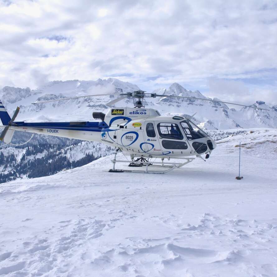 white and blue helicopter on snow covered ground